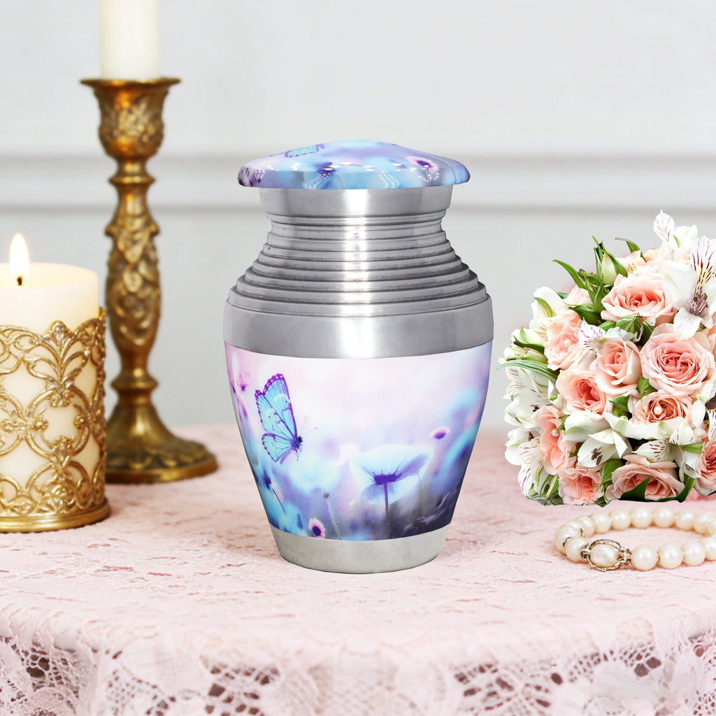 Cremation containers with blue butterflies, decorative ash urn with screw lid, table display with flowers and candlestick