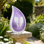 Elegant purple angel wing teardrop urns for ashes resting on stone garden pillar for outdoor cemetery remembrance