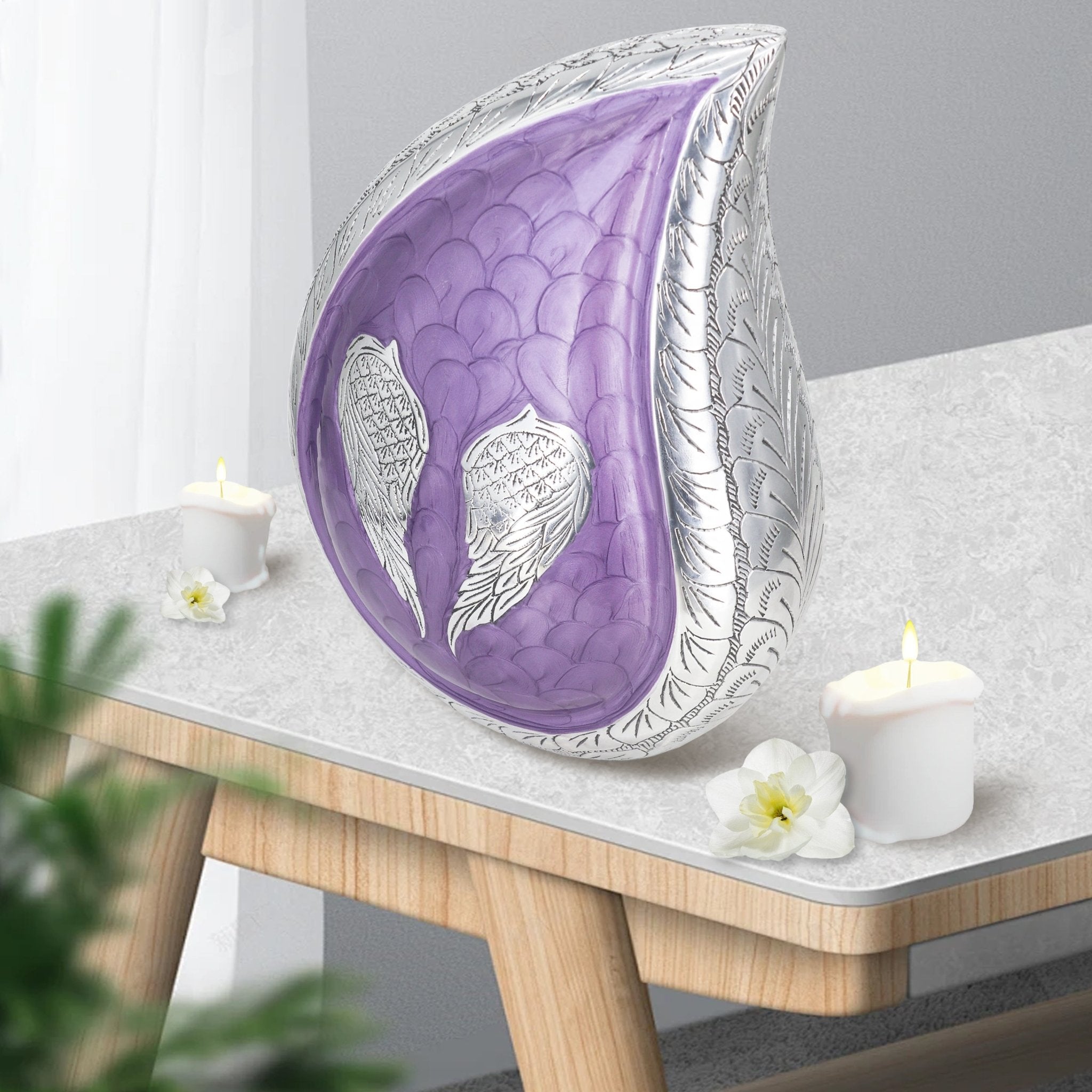 Purple engraved angel wings teardrop metal funeral urn placed on wooden side table with candles for home mantel decor