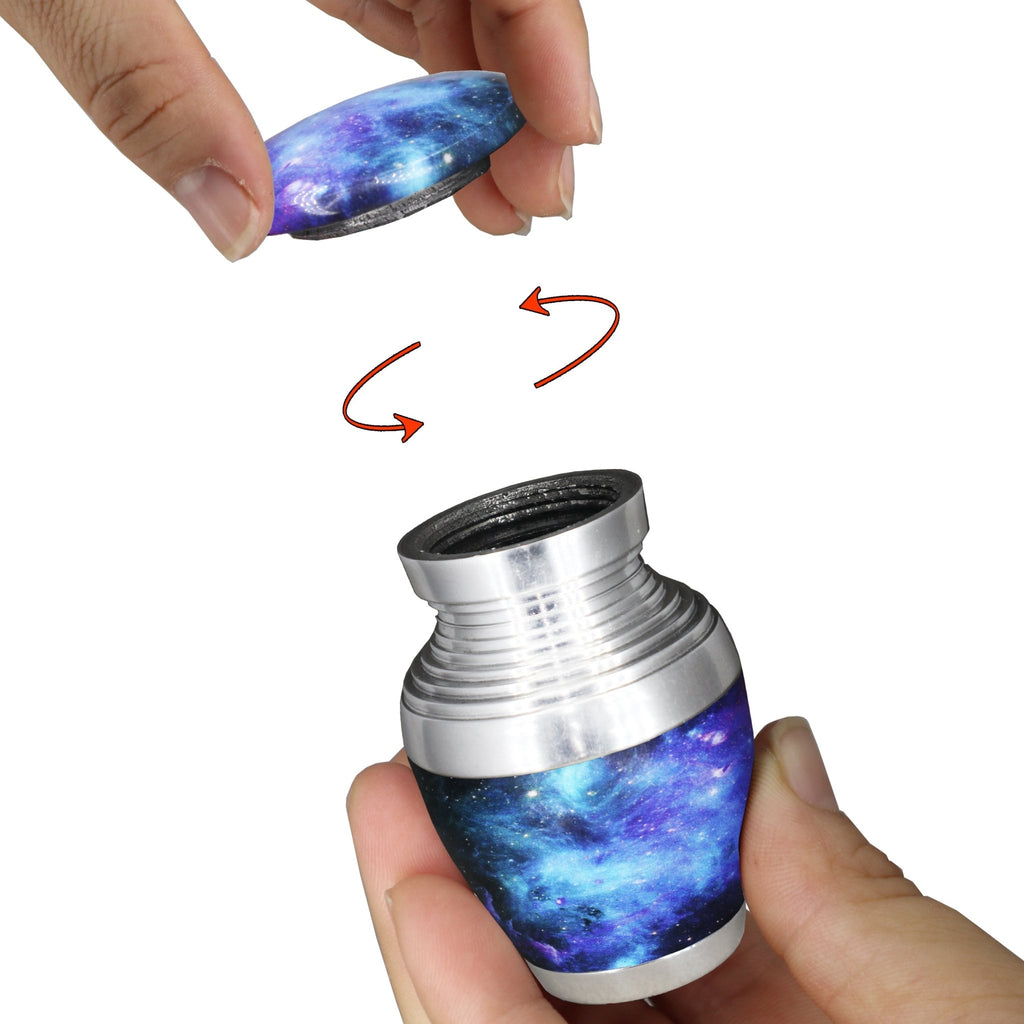 Mini urn for ashes with blue galaxy nebula artwork and secure threaded screw-top lid shown opened by hand