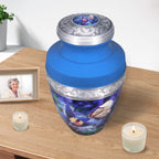 Urns for cremated remains beside candles, blue floral memorial for mother with engraved aluminum craftsmanship