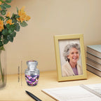 Tiny urns for ashes with purple butterfly flowers displayed near a family portrait for a treasured dad