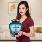 Woman holding a large urn for human ashes with turquoise cross artwork, showing the adult memorial urn for scale