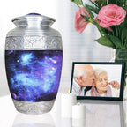 Blue galaxy funeral urn displayed beside a family memorial portrait and pink flowers for peaceful remembrance