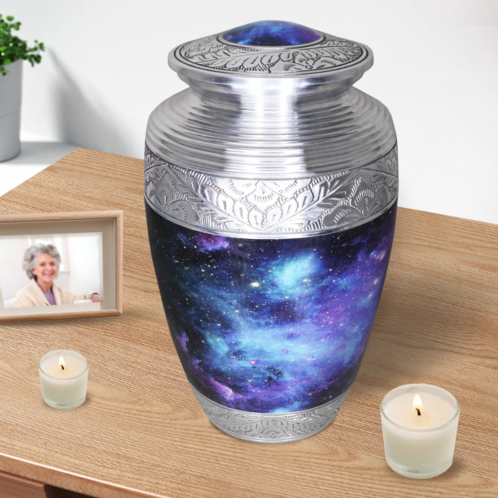 Blue memorial urn for ashes with cosmic galaxy artwork displayed at home with remembrance candles and family decor
