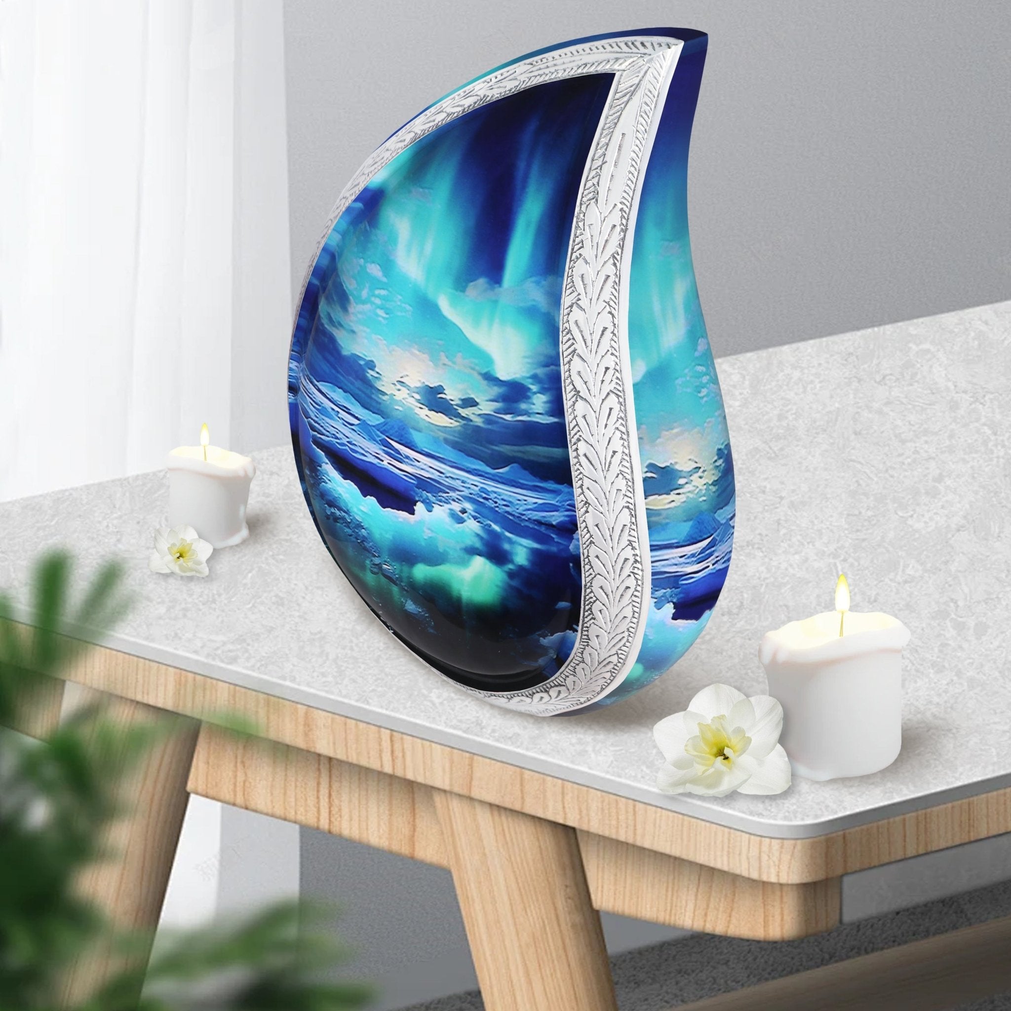 Northern lights teardrop memorial ash vessel set on light wood side table with candles for indoor mantel tribute decor
