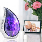 Purple galaxy funeral urn displayed beside pink roses and a framed memorial portrait for remembrance