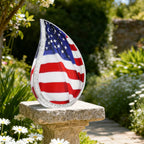 Patriotic US flag teardrop burial urns engraved aluminum urn resting on stone garden pillar for veteran tribute