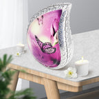 Pastel purple butterflies aluminum adult urn set on light wood side table with candles for warm indoor remembrance
