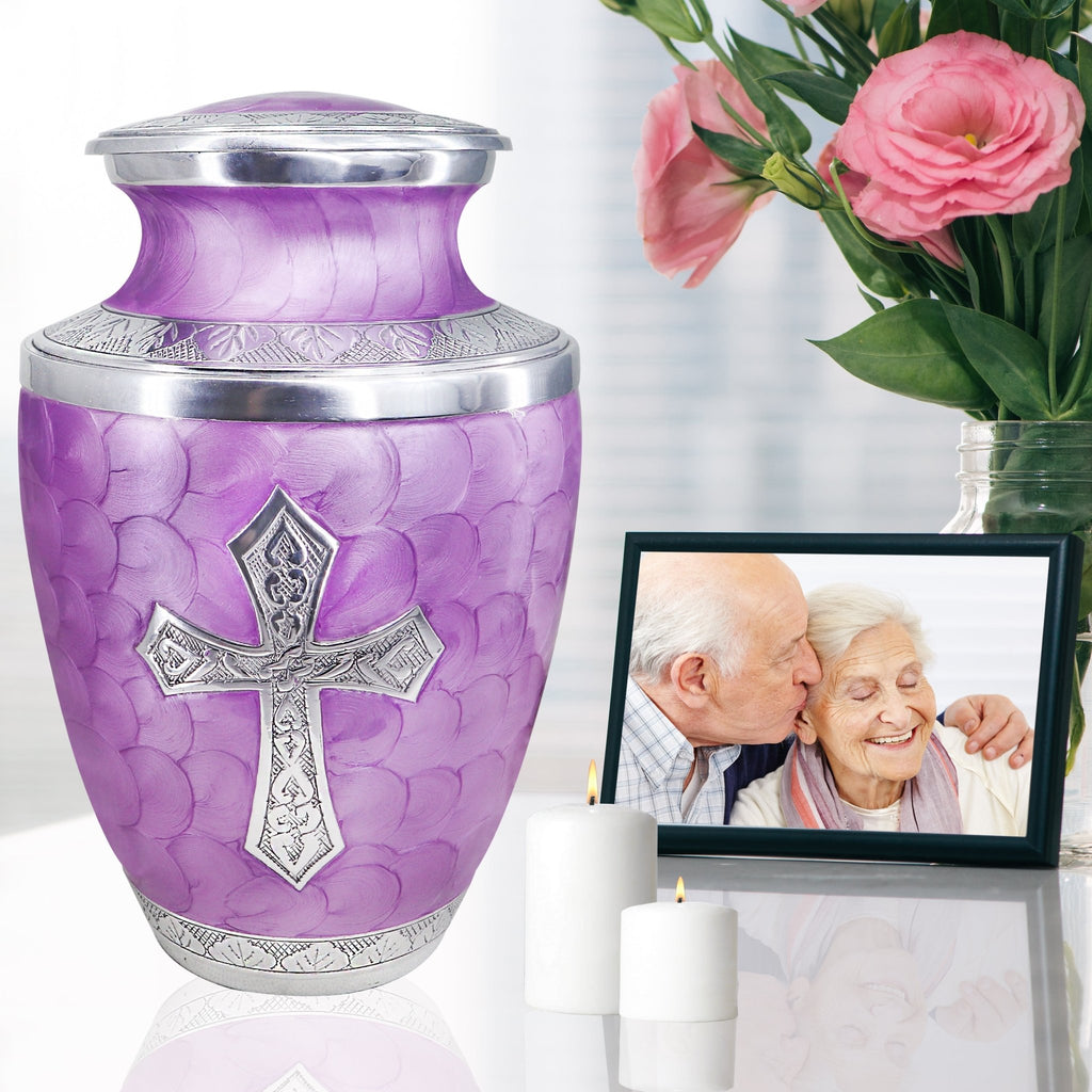 Purple cremation urns for human ashes adult beside family photo and flowers, elegant tribute for mother with Christian cross