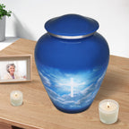 Modern Christian urn for ashes with bright cross and cloud design displayed with candles for peaceful home memorial