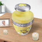 Urns for cremated remains beside candles, butterfly tribute for mother with engraved aluminum craftsmanship