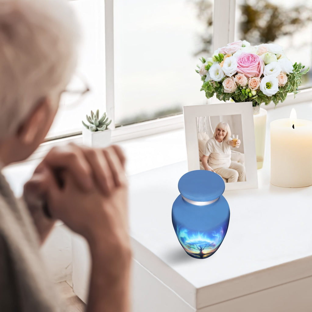 Cremation urns for human ashes with a blue Tree of Life, woman remembering her beloved husband at home