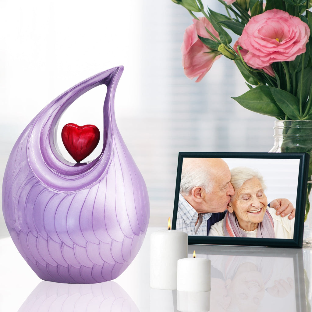 Purple heart urn beside photo frame and roses, sentimental keepsake urns for human ashes to honor loved ones
