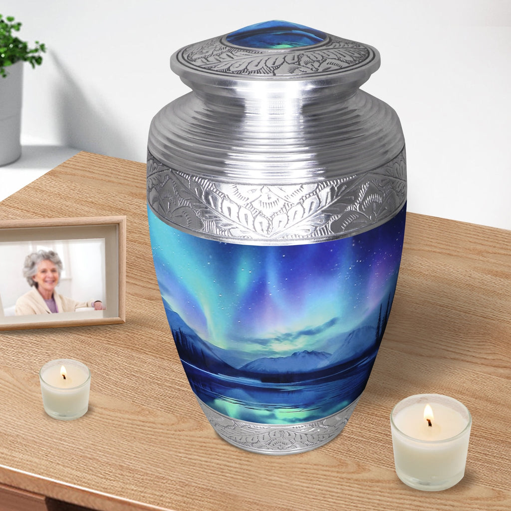 Adult urn for human ashes with Northern Lights artwork displayed at home with memorial candles and a framed photo