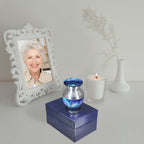 Memorial ashes keepsake with Aurora Borealis design displayed on a blue presentation box beside a family portrait