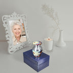 Cremation containers with butterfly sky design, small memorial urn with screw lid, displayed with photo frame and candle