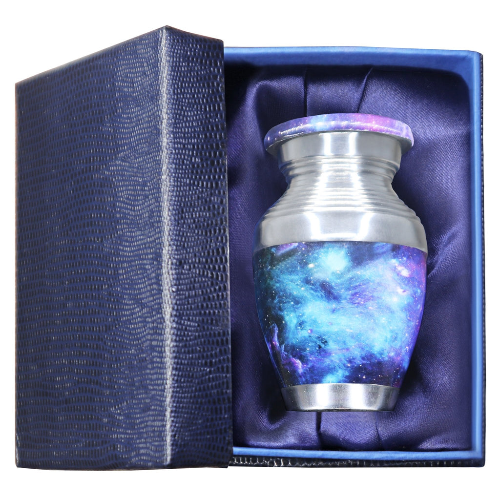 Metal keepsake urn for ashes with blue cosmic galaxy artwork presented in a padded blue memorial gift box
