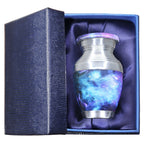 Metal keepsake urn for ashes with blue cosmic galaxy artwork presented in a padded blue memorial gift box