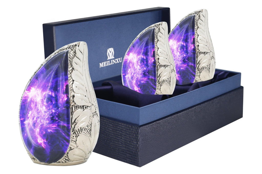 Set of 3 mini urns for ashes with purple cosmic galaxy artwork arranged in a blue presentation box