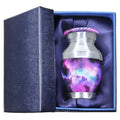 Keepsake urn for ashes with purple cosmic galaxy artwork presented in a padded blue memorial gift box