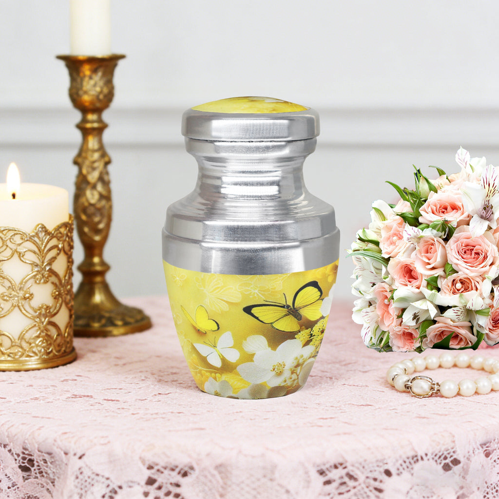 Small urns for ashes with butterfly artwork beside candles and flowers, a loving tribute for mother at home