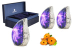 Cosmic galaxy ashes keepsake set with three purple brass mini urns, blue presentation box and orange flowers