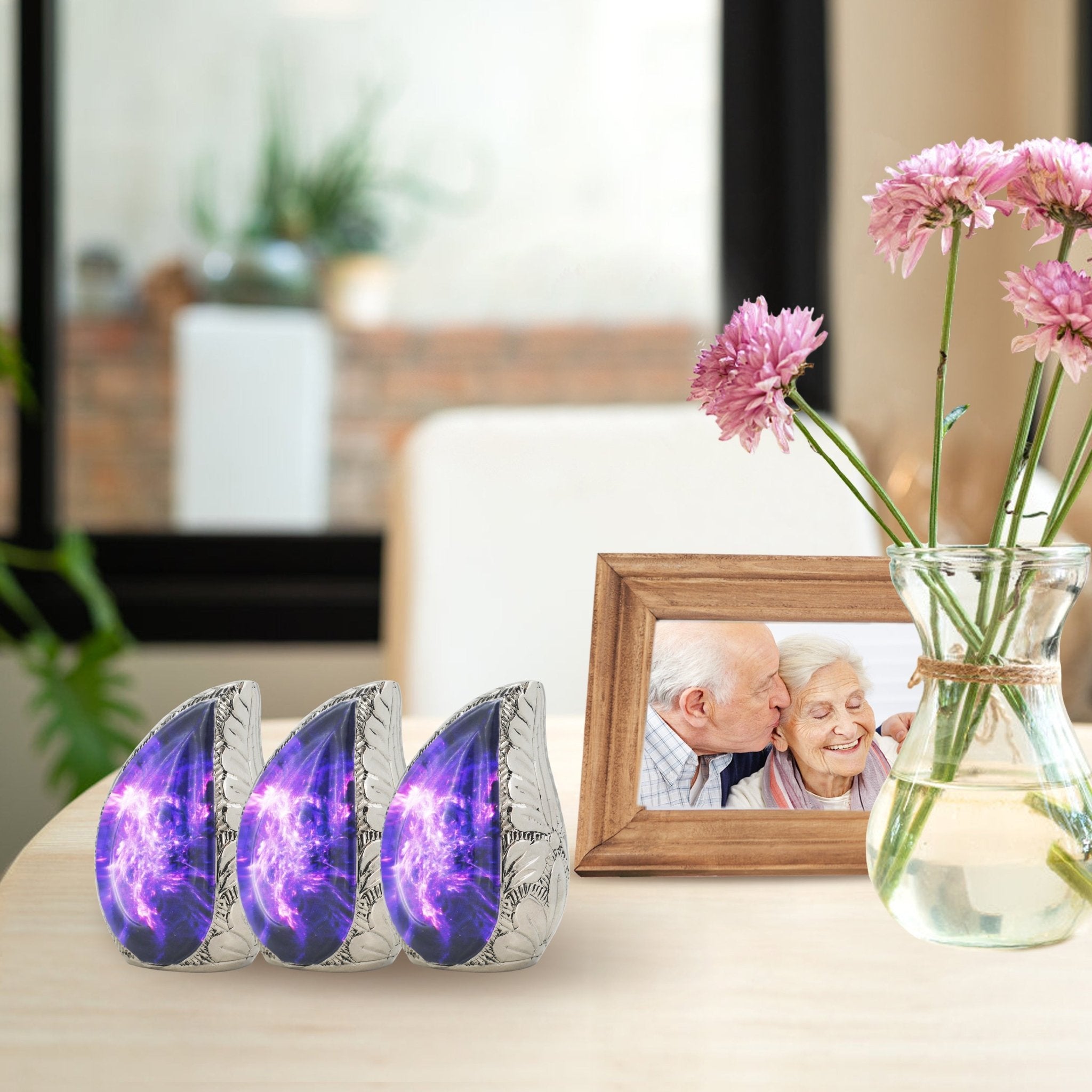 Urns and keepsakes for ashes with three purple galaxy mini urns displayed beside flowers and a framed photo