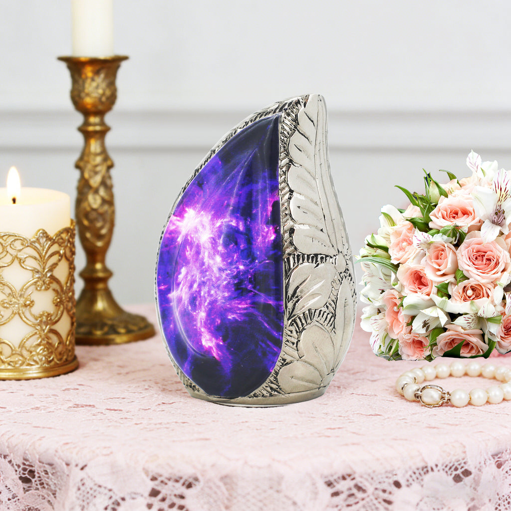 Decorative purple galaxy keepsake urn displayed on a lace memorial table with roses and a gold candlestick