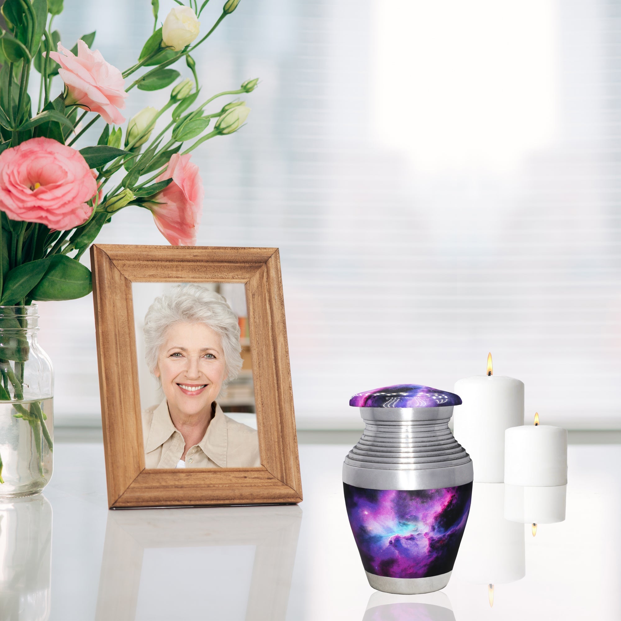 Small remembrance urn with purple nebula artwork displayed beside a framed memorial photo and candles