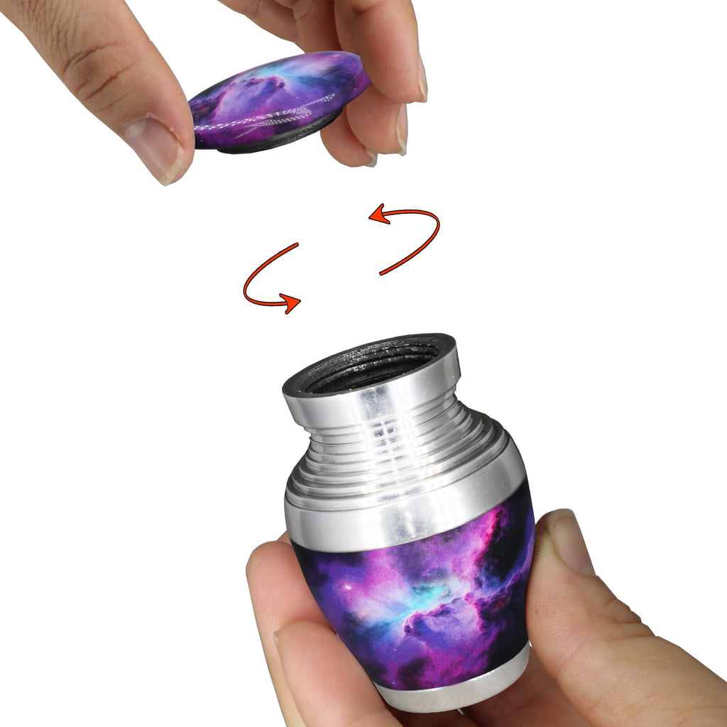 Mini urn for ashes with purple cosmic galaxy artwork and secure threaded screw-top lid shown opened by hand