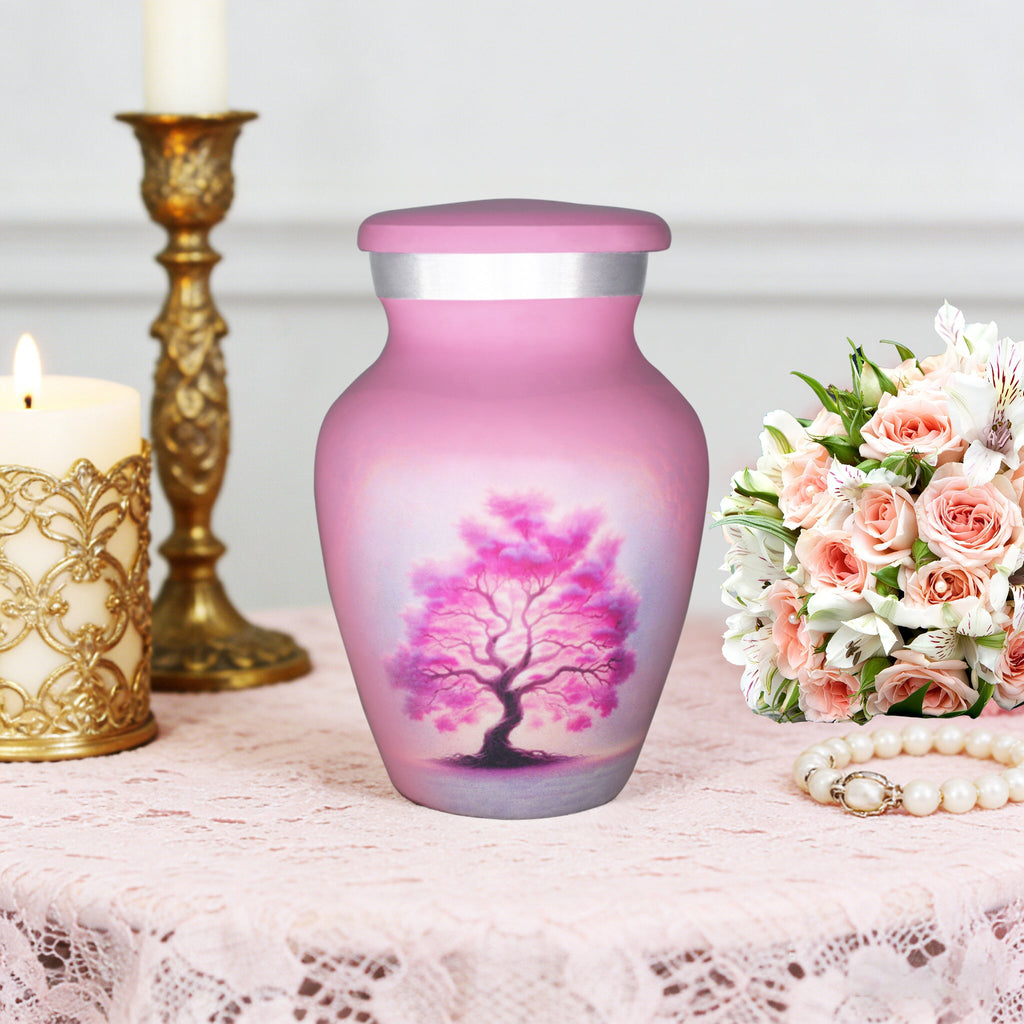 Small urns for ashes featuring a pink Tree of Life, displayed with candles and flowers for dad's remembrance