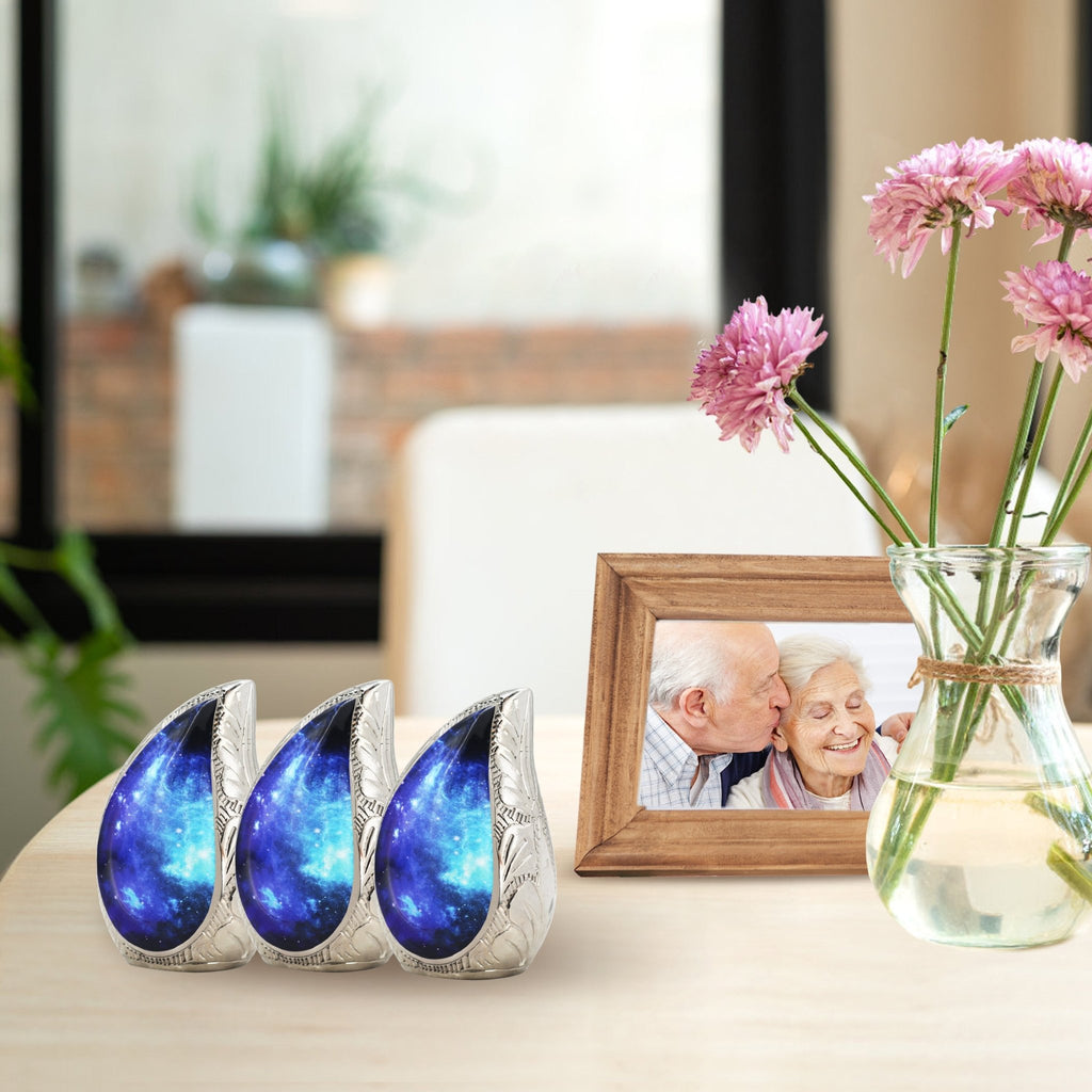 Three matching blue cosmic engraved brass small ash urns grouped on living room shelf for shared family ashes