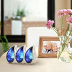 Three matching blue cosmic engraved brass small ash urns grouped on living room shelf for shared family ashes