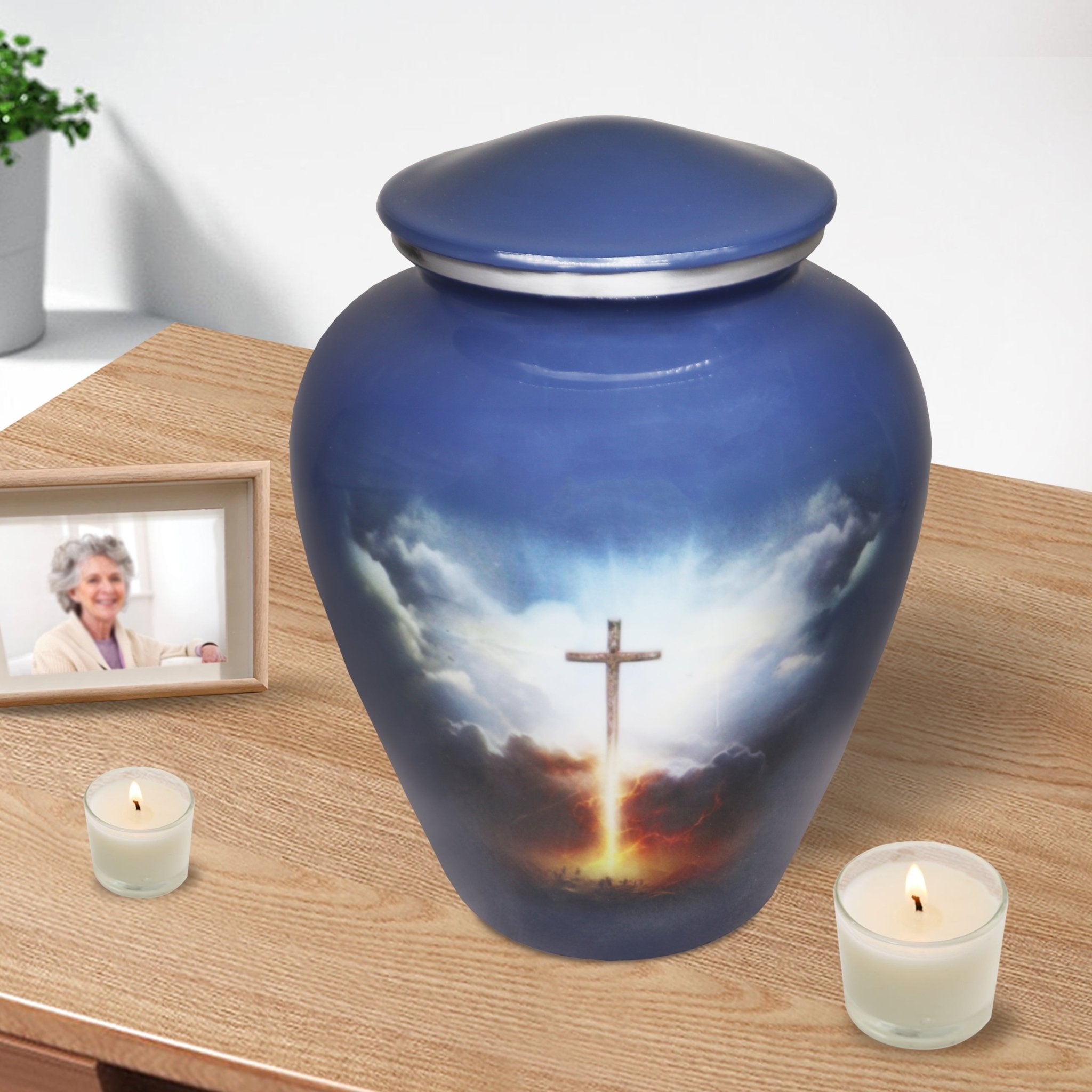 Religious cremation urn with grey blue Cross of Life artwork displayed with candles for peaceful home memorial
