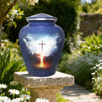 Grey blue cross memorial urn displayed outdoors on a garden stone among green foliage for peaceful remembrance